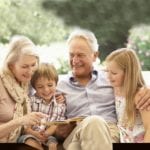 older couple sit with grandchildren