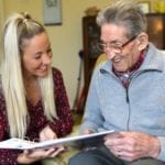 care giver and older man look at a book together