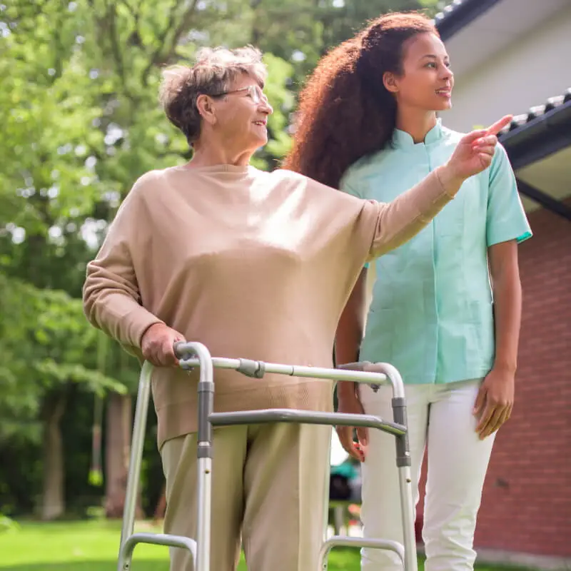 A compassionate woman providing precious support to an elderly woman with a walker.