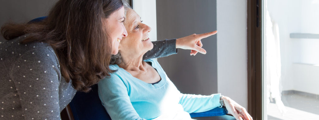 Two elderly women choosing a care home while pointing at a window.