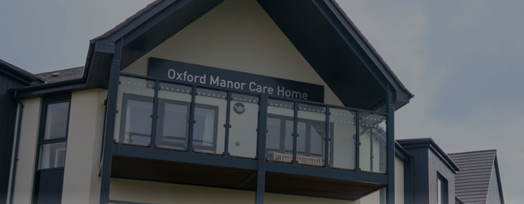 Exterior view of a building with a sign reading Oxford Manor Care Home above a glass balcony.