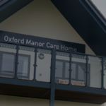 Exterior view of a building with a sign reading Oxford Manor Care Home above a glass balcony.