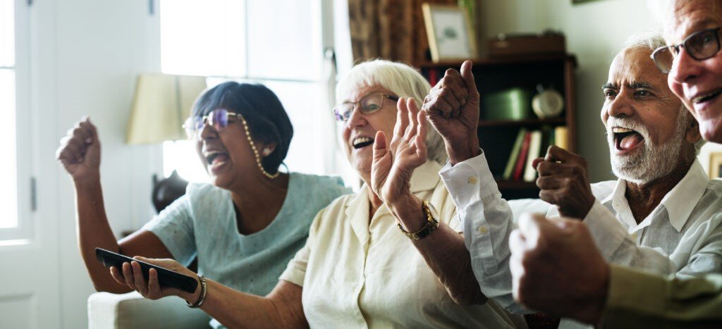 senior people in care home watching television laughing