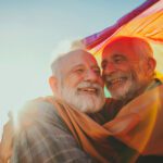 two older men hugging each other with rainbow flag