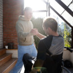 young man in wheelchair and friend clasp hands
