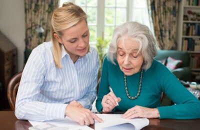 MyLife MyCare lead imageolder lady and carer sat at table writing